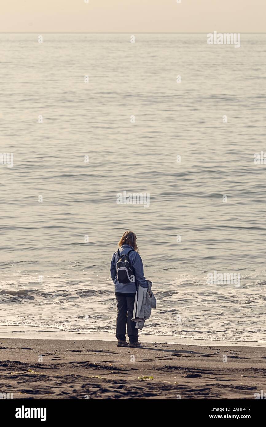 Heitere Szene einer Frau mit Blick auf das Meer am Strand Stockfoto