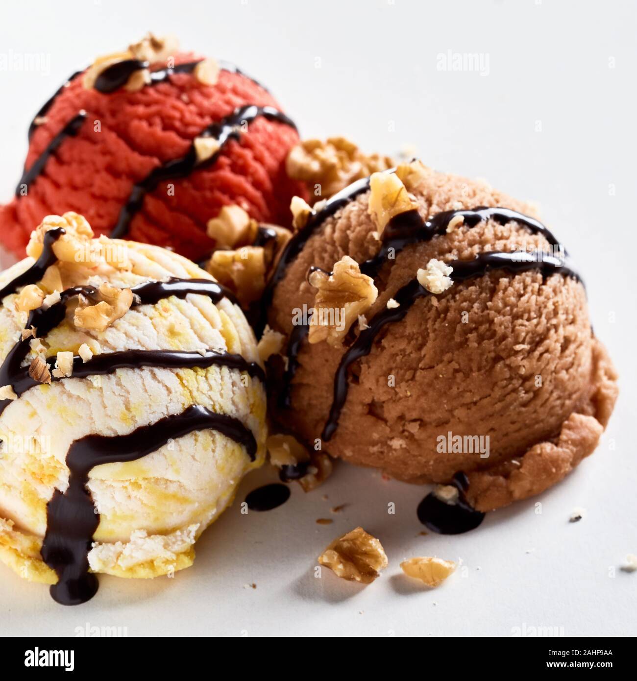 Drei Kugeln aromatisiert gefrorenes Eis mit gehackten Walnüssen garniert und beträufelt Schokolade in der Nähe zu sehen. Stockfoto