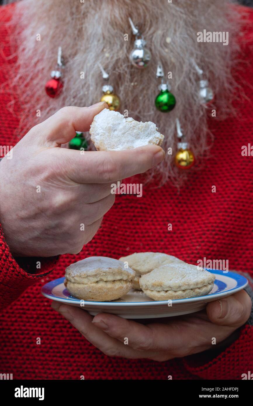 Mann essen mince pies mit einem langen, weißen Bart und Spielereien an Weihnachten Stockfoto