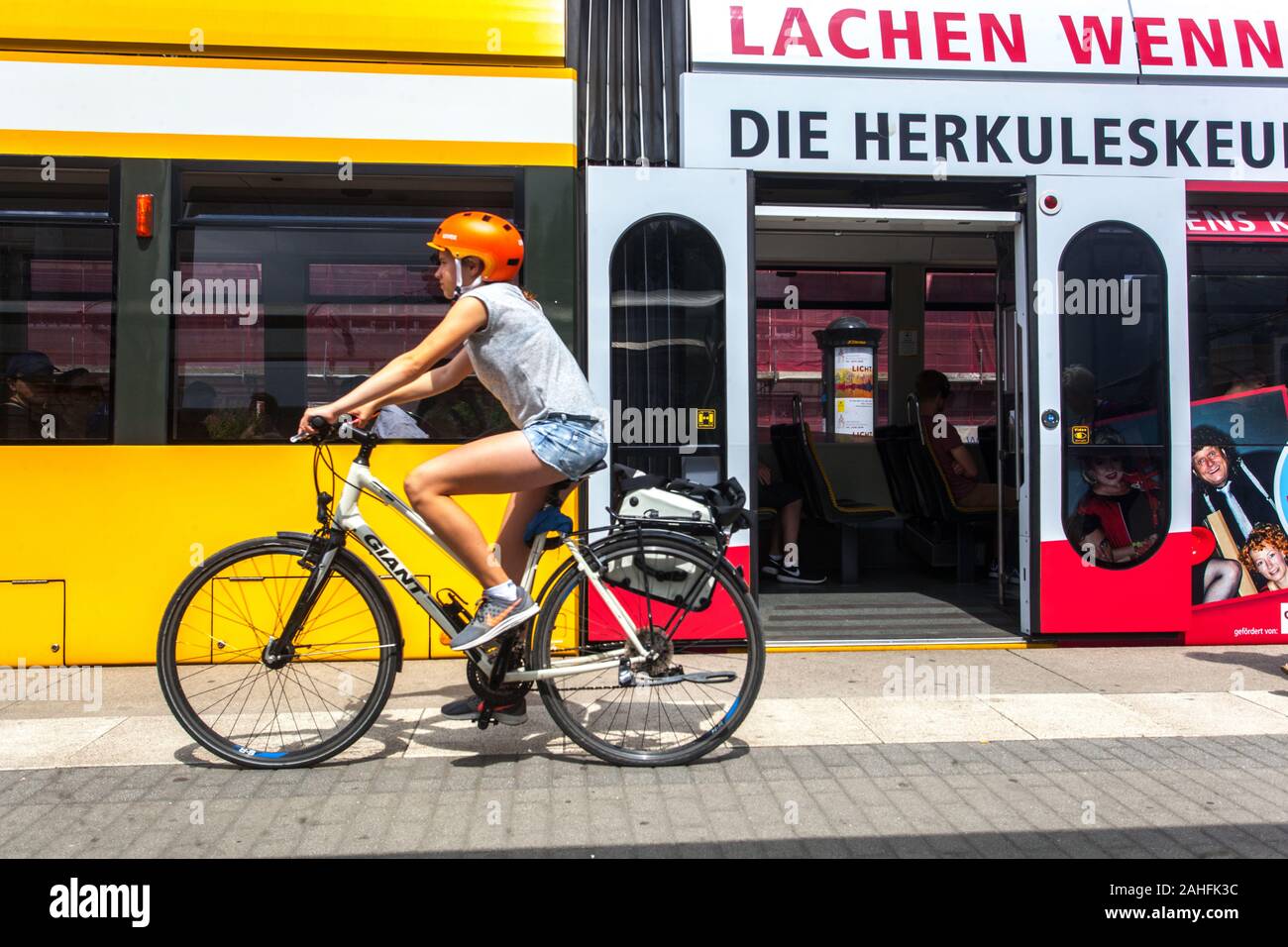 Junges Mädchen, das auf einem Fahrrad in der Innenstadt fährt, Straßenbahnhaltestelle Dresden Deutschland Stadtfahrrad Stadtkind, das Fahrrad mit Helm fährt Stockfoto