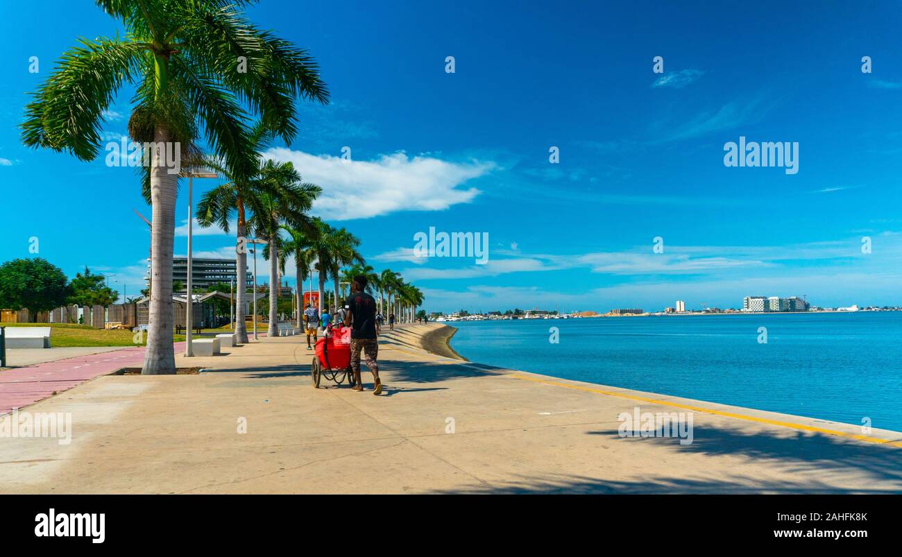 Luanda, angolanischer Zeit - 15. Dezember 2019: Menschen, die an einem sonnigen Tag in der Bucht von Luanda spazieren gehen. Redaktionelle Illustration. Stockfoto