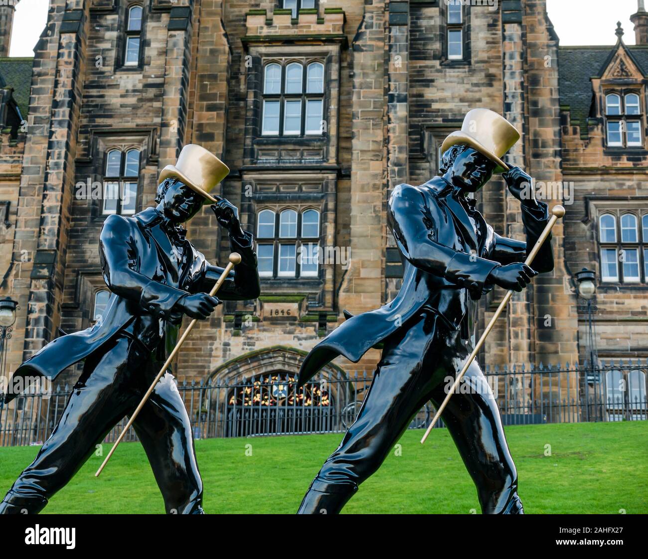 Edinburgh, Schottland, Vereinigtes Königreich. 29. Dezember 2019. Neue Jahr feiern: Sunshine in der Innenstadt wie die Hogmanay Festlichkeiten eingestellt sind. Die sieben Johnnie Walker schreitenden Männer Statuen auf dem Damm vor der Montage Gebäude; die Hogmanay street Party wird von der Whiskymarke Johnnie Walker Stockfoto