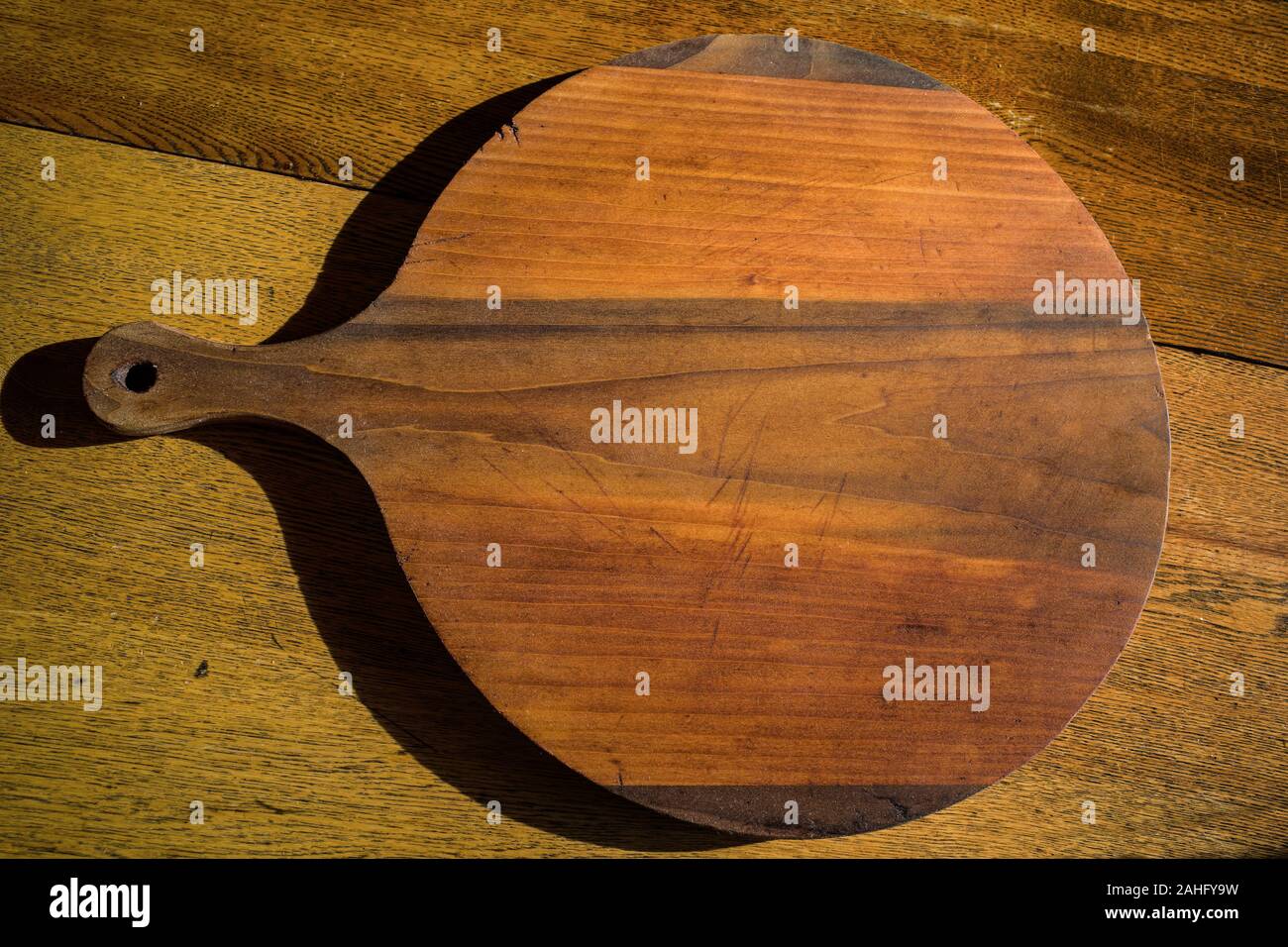 Antike Kuchen oder Gebäck Board auf antike Eiche Esstisch in natürlichem Sonnenlicht gelegt. Die Boards werden verwendet, um den Teig vor dem Backen Zubereiten. Stockfoto
