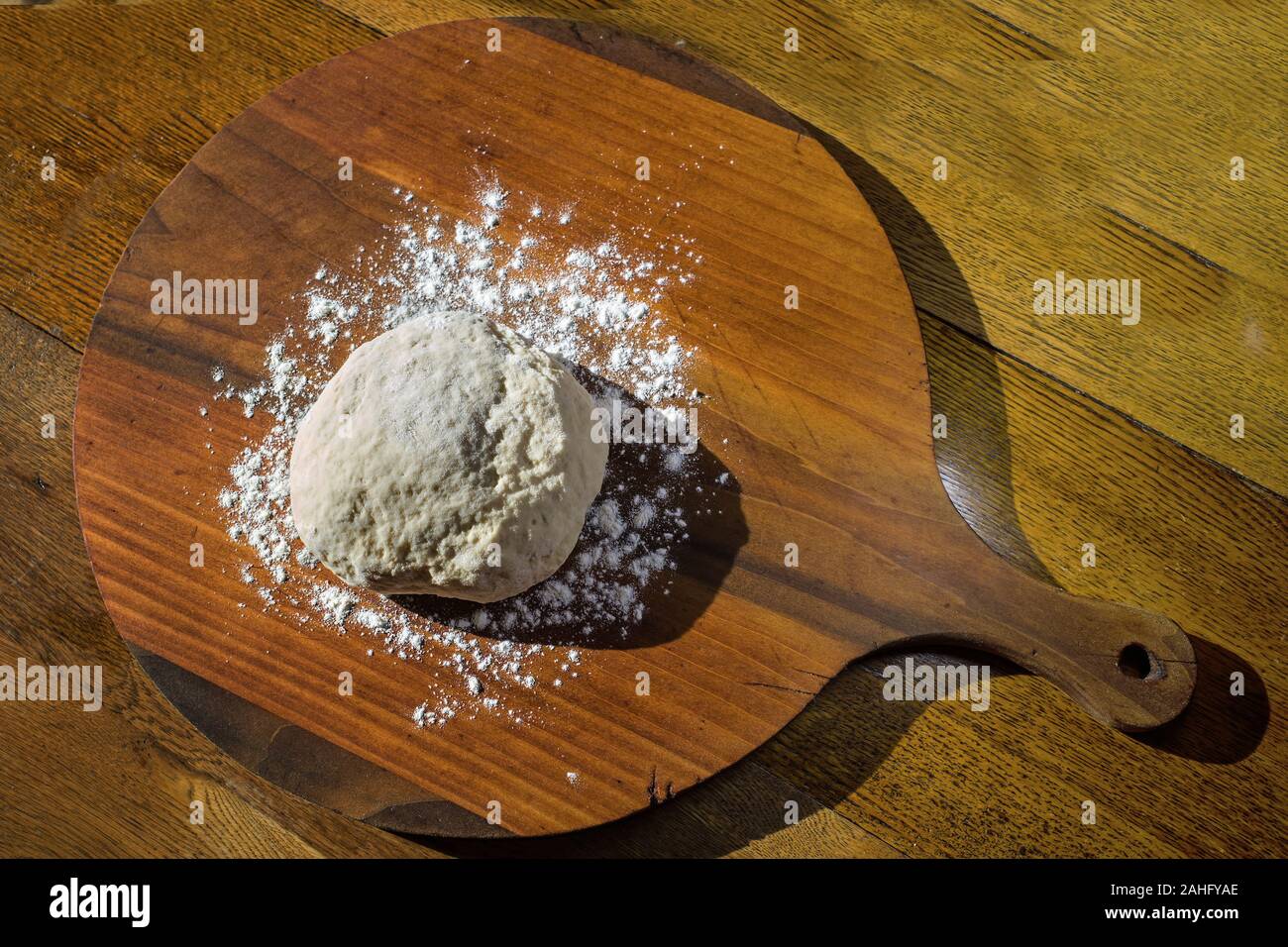 Antike Kuchen oder Gebäck Board auf antike Eiche Esstisch in natürlichem Sonnenlicht gelegt. Die Boards werden verwendet, um den Teig vor dem Backen Zubereiten. Stockfoto