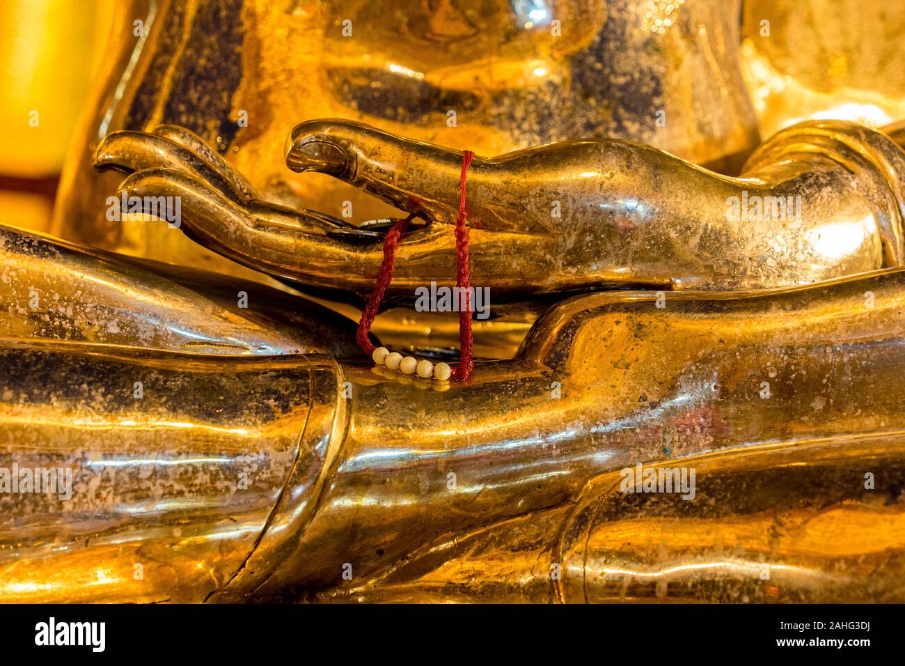 Nahaufnahme Detail der Hand auf einer goldenen Buddha-Statue, mit einer Gabe von Perlen drapiert über den Daumen Stockfoto