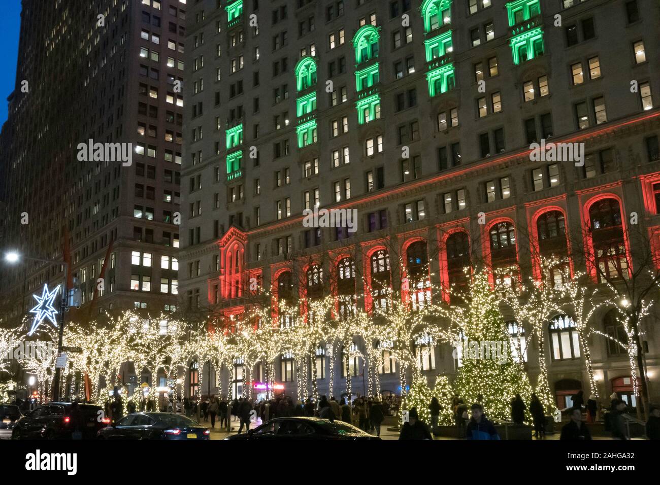 Zuccotti Park mit der Dreifaltigkeit und United States Immo Gebäude im Hintergrund ist hell erleuchtet in der Weihnachtszeit, NYC, USA Stockfoto
