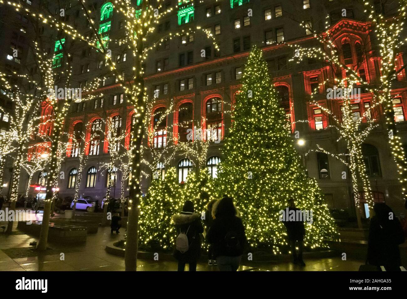 Zuccotti Park mit der Dreifaltigkeit und United States Immo Gebäude im Hintergrund ist hell erleuchtet in der Weihnachtszeit, NYC, USA Stockfoto