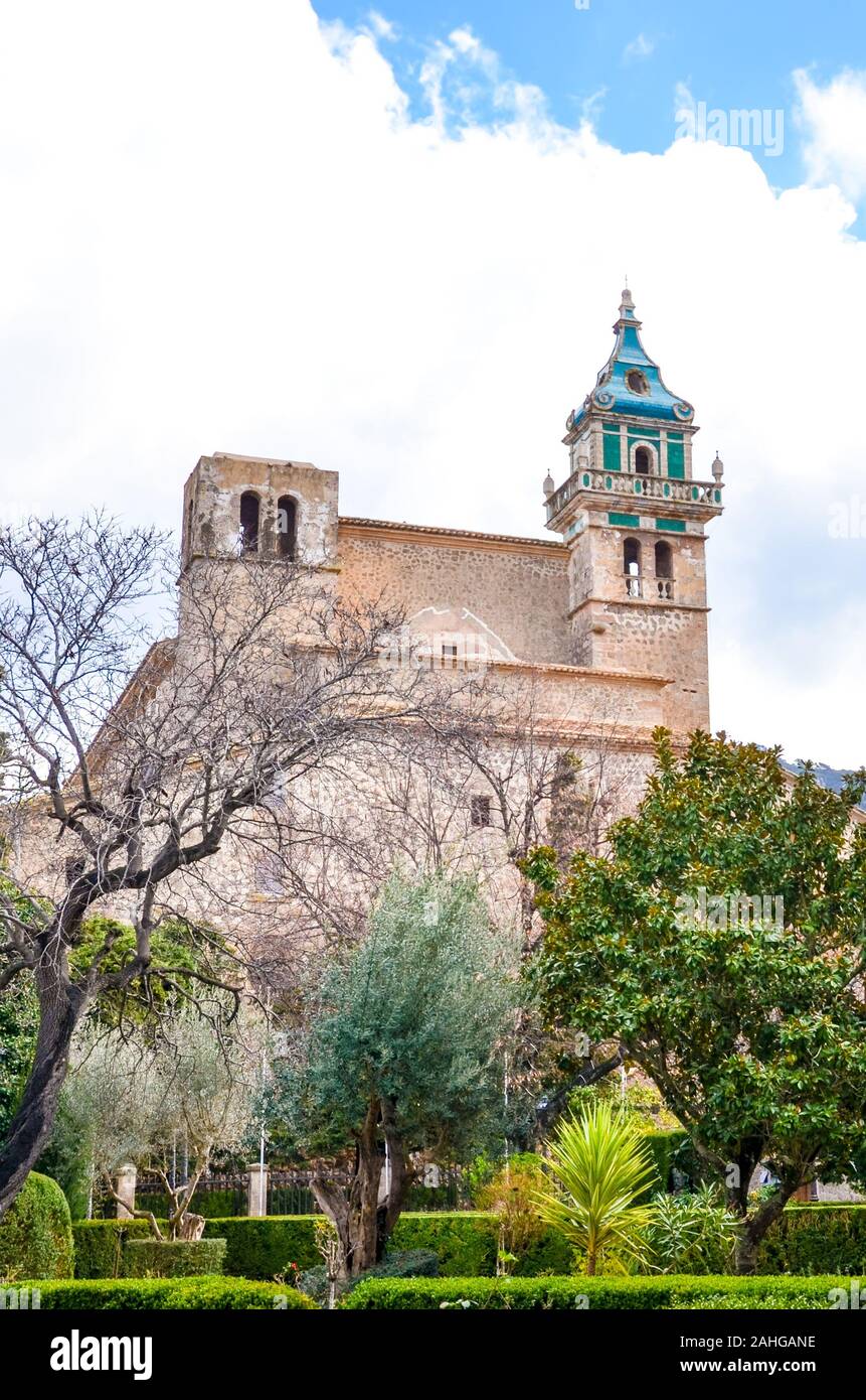 Das Gebäude der Kartause von Valldemossa, in Valldemossa, Mallorca, Spanien von grünen Bäumen im Hof umgeben. Berühmte Kartause von Valldemossa, Spanisch touristische Attraktion. Stockfoto