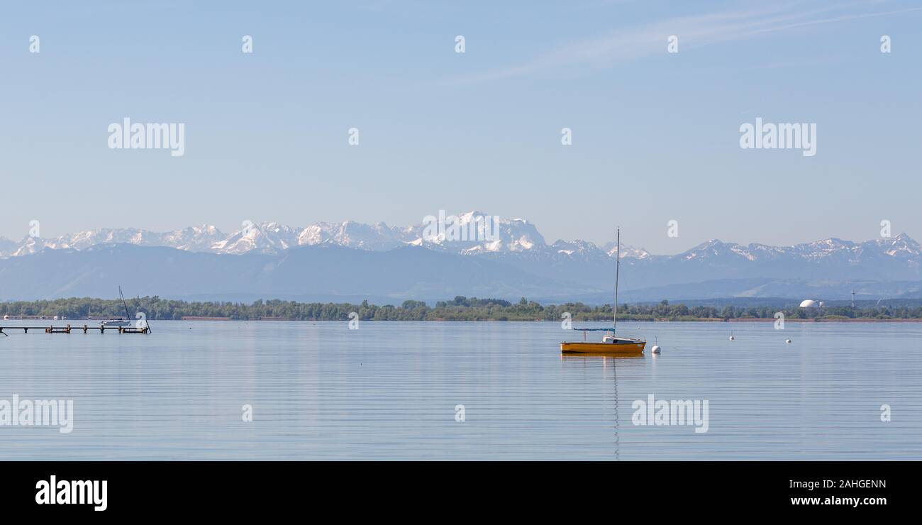 Panoramasicht auf den Ammersee mit orangefarbenem segelboot und Wettersteingebirge im Hintergrund. Der schneebedeckte Gipfel in der Mitte ist Zugspitze. Stockfoto