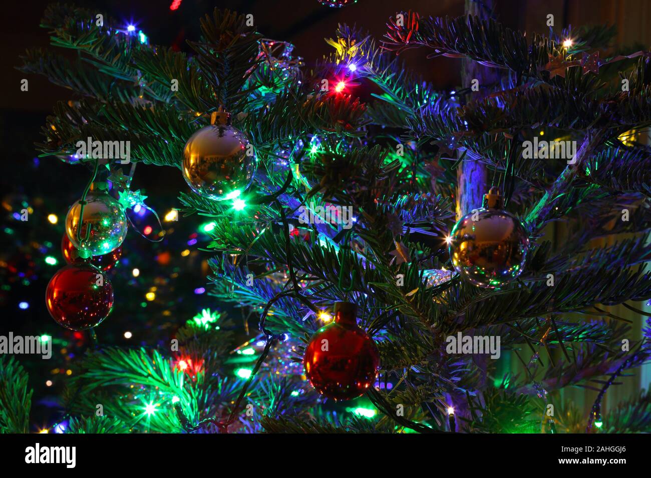 Nahaufnahme eines Teils der Weihnachtsbaum mit Dekoration, Christbaumkugeln, Lametta, Sterne und Lichterketten, Haslemere, Surrey, Großbritannien. Stockfoto