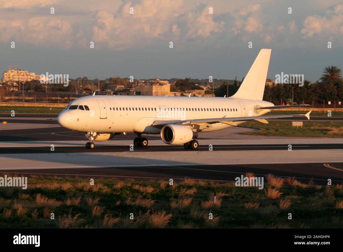 Flugreisen und Zivilluftfahrt. Unmarkiertes Airbus A320-Passagierflugzeug auf der Start- und Landebahn bei Sonnenuntergang. Titel, Logo oder Logo der Fluggesellschaft sind nicht sichtbar. Stockfoto