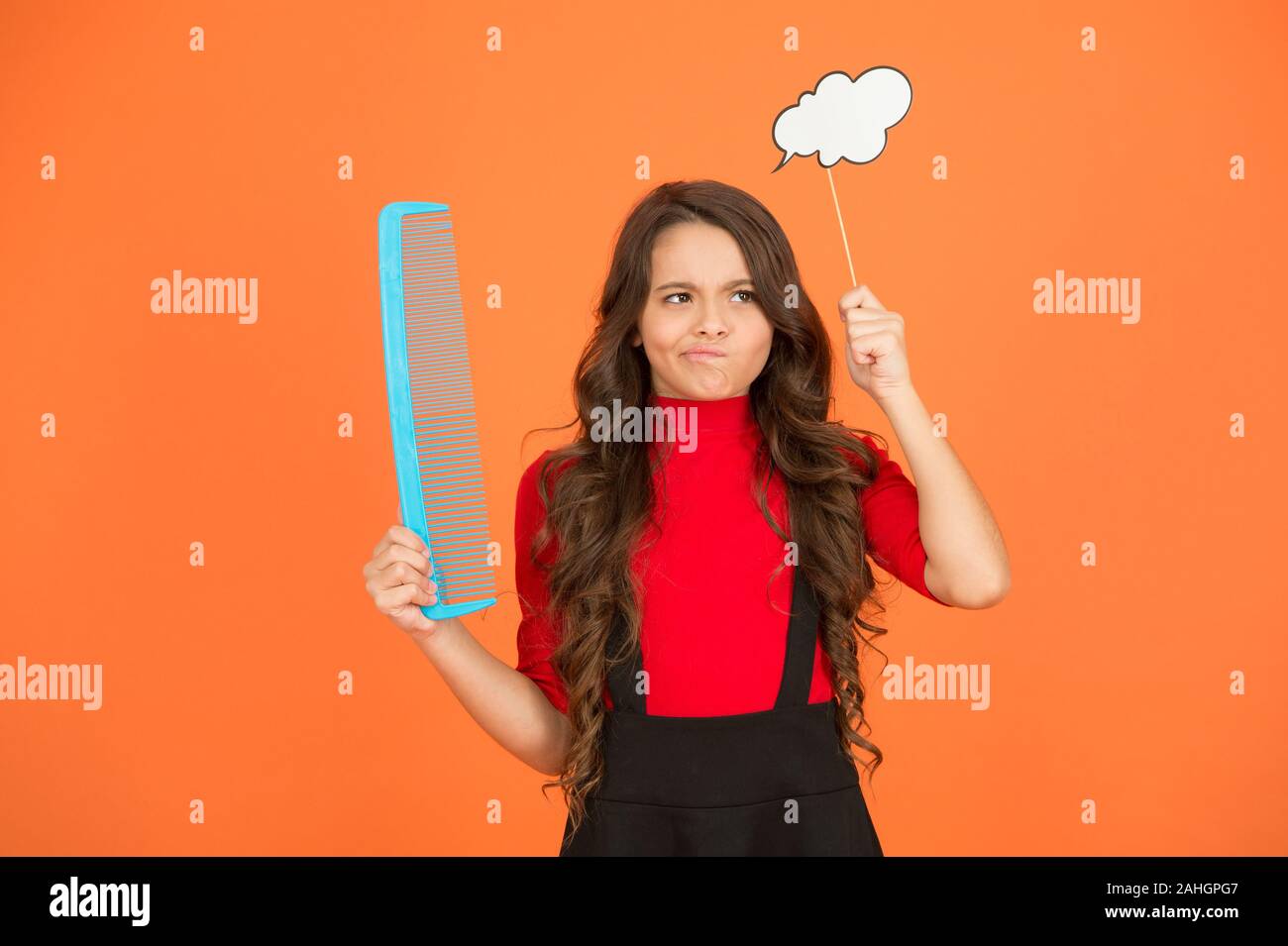 Wachsendes Haar Empfehlung. Kind mit lockigem Haar. Friseur für Kid. Beauty und Mode. denken an neue Frisur. Schulmädchen halten großen Kammaufsatz. Pflege und bürsten Sie Ihr Haar. Kleines Mädchen lange Haare. Stockfoto