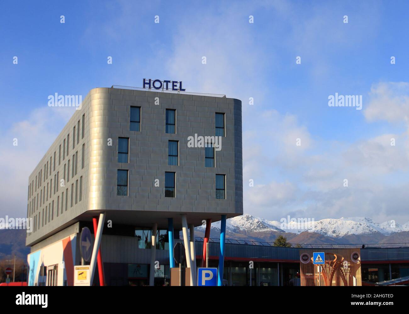 Modernes Hotel mit Stahl Fliesen, Italienische Alpen Landschaft, im Jahr 2006 die Winter Olympiade gebaut. Sie sehen eine Reproduktion der Olympischen Fackel aus Holz Stockfoto