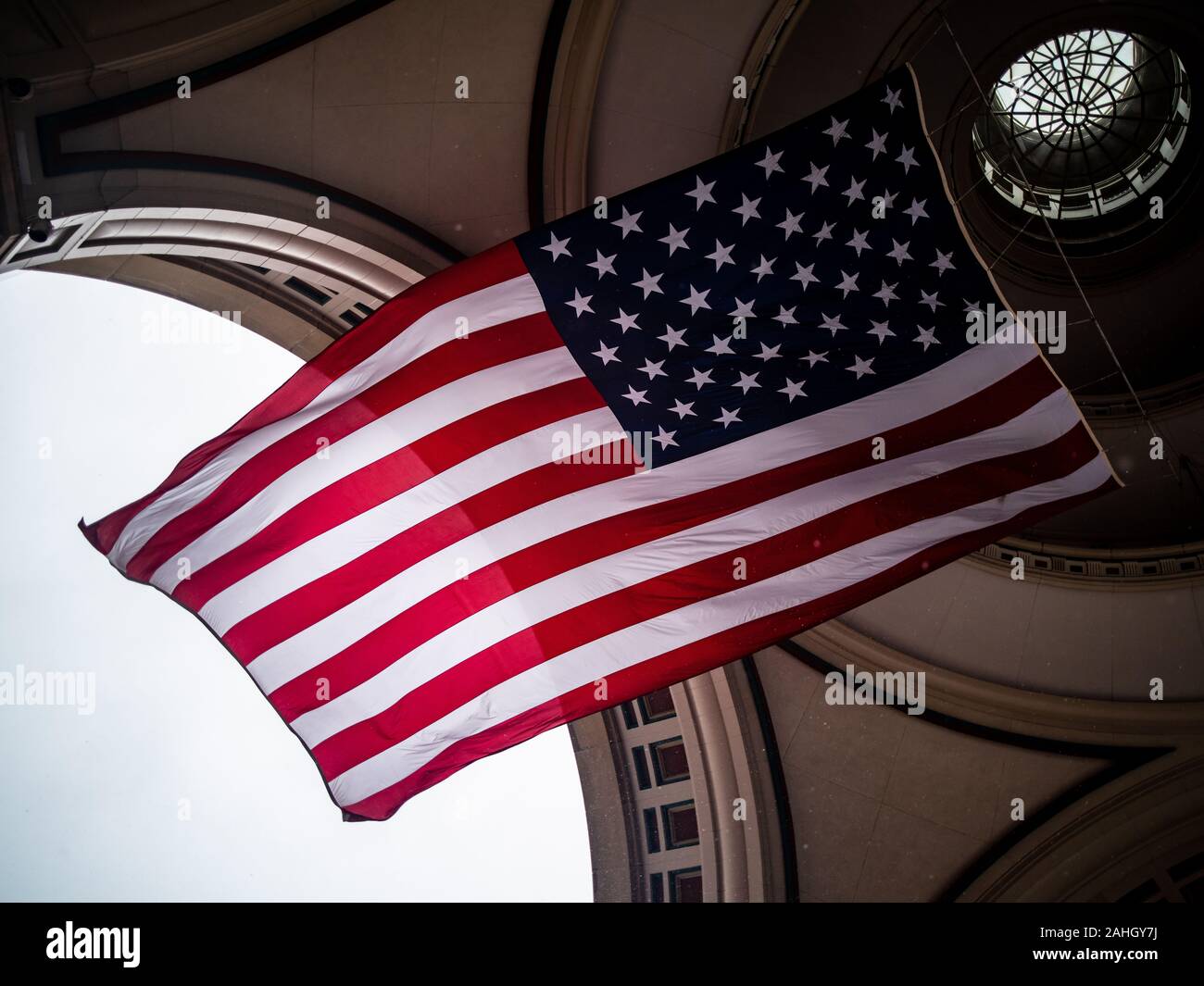 Die amerikanische Flagge fliegt hoch unter einem Bogen Stockfoto