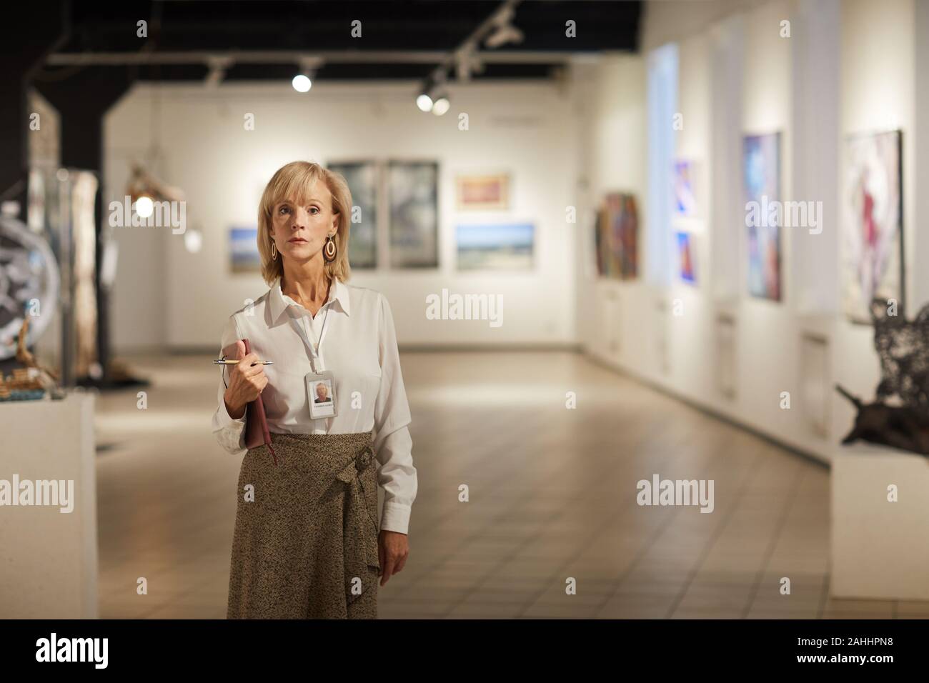 Portrait von reife weibliche Experten in der Galerie für Moderne Kunst Halle an Kamera suchen und halten Zwischenablage Posing, kopieren Raum Stockfoto