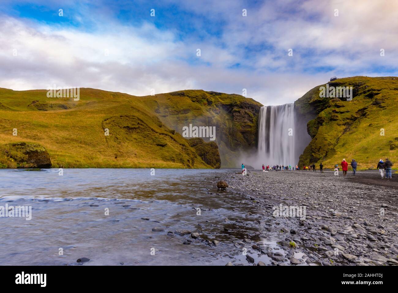 Skogafoss Wasserfall aus der Ferne mit unkenntlich Besucher, mit einer teilweise bedecktem Himmel am Ende eines frühen Oktober Nachmittag gesehen, Island Stockfoto