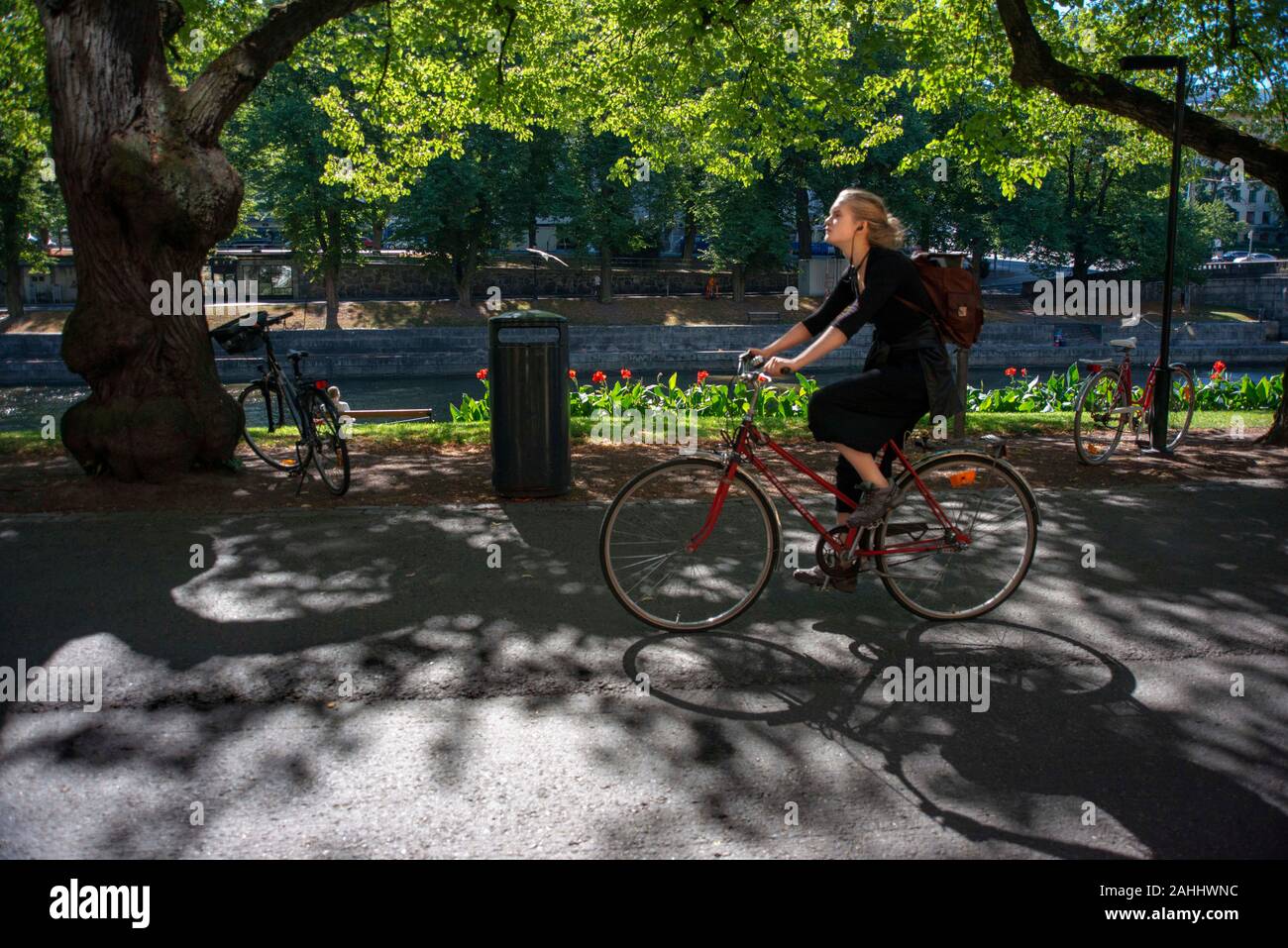 Frau auf einem Fahrrad auf einer Promenade am Ufer des Flusses Aura in Turku, Finnland. Stockfoto