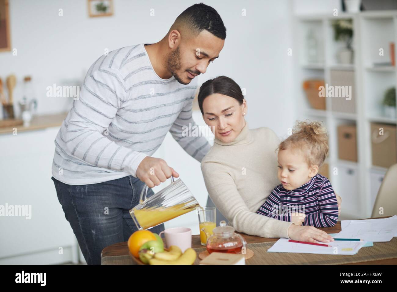 Portrait von Happy mixed-race Familie trinken Orangensaft, während morgen zusammen zu Hause genießen, kopieren Raum Stockfoto