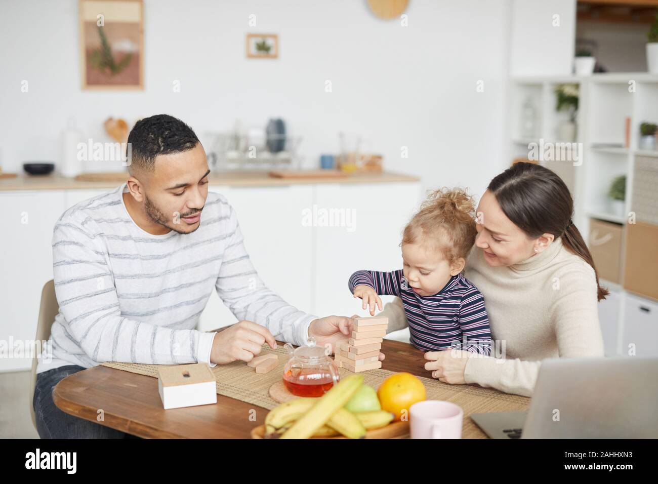 Portrait von Happy mixed-race Familie spielen mit niedlichen kleinen Tochter beim Frühstück zu Hause, Kopie Raum Stockfoto