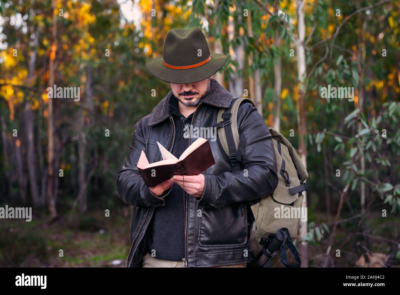 Reifer Mann mit Hut und Jacke Suche altes Buch am Wald mit Platz für Text kopieren Stockfoto
