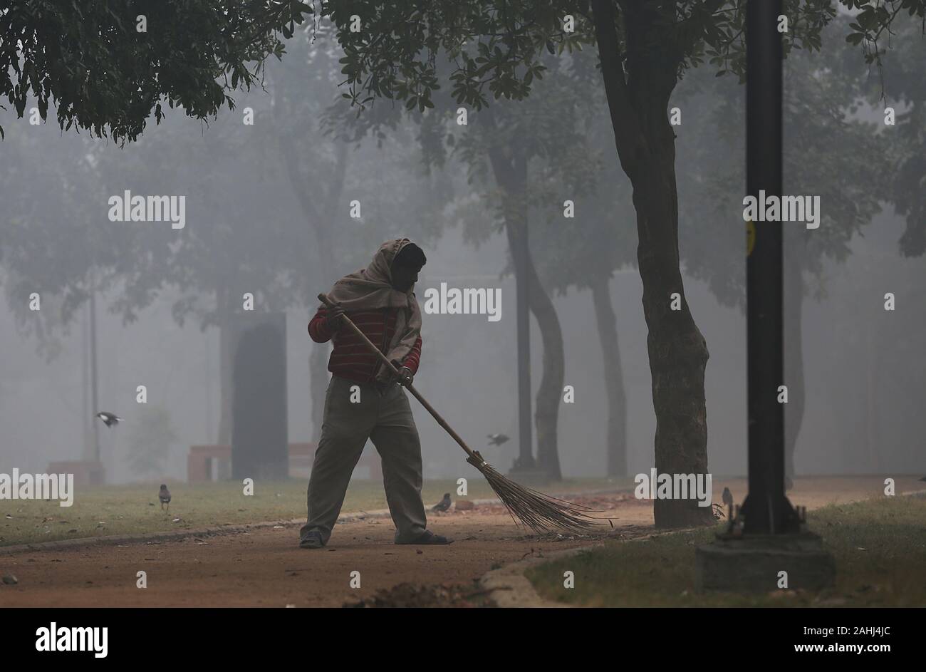 New Delhi. 30 Dez, 2019. Eine sauberere fegt die Masse an einen öffentlichen Park inmitten von dichten Nebel in Neu Delhi, Dez. 30, 2019. Dichten Decke von Nebel der indischen Hauptstadt Neu Delhi und Stadtrand Montag Morgen bedeckt, die zu Störungen im Luft- und Schienenverkehr, sagten Beamte. Credit: Javed Dar/Xinhua/Alamy leben Nachrichten Stockfoto