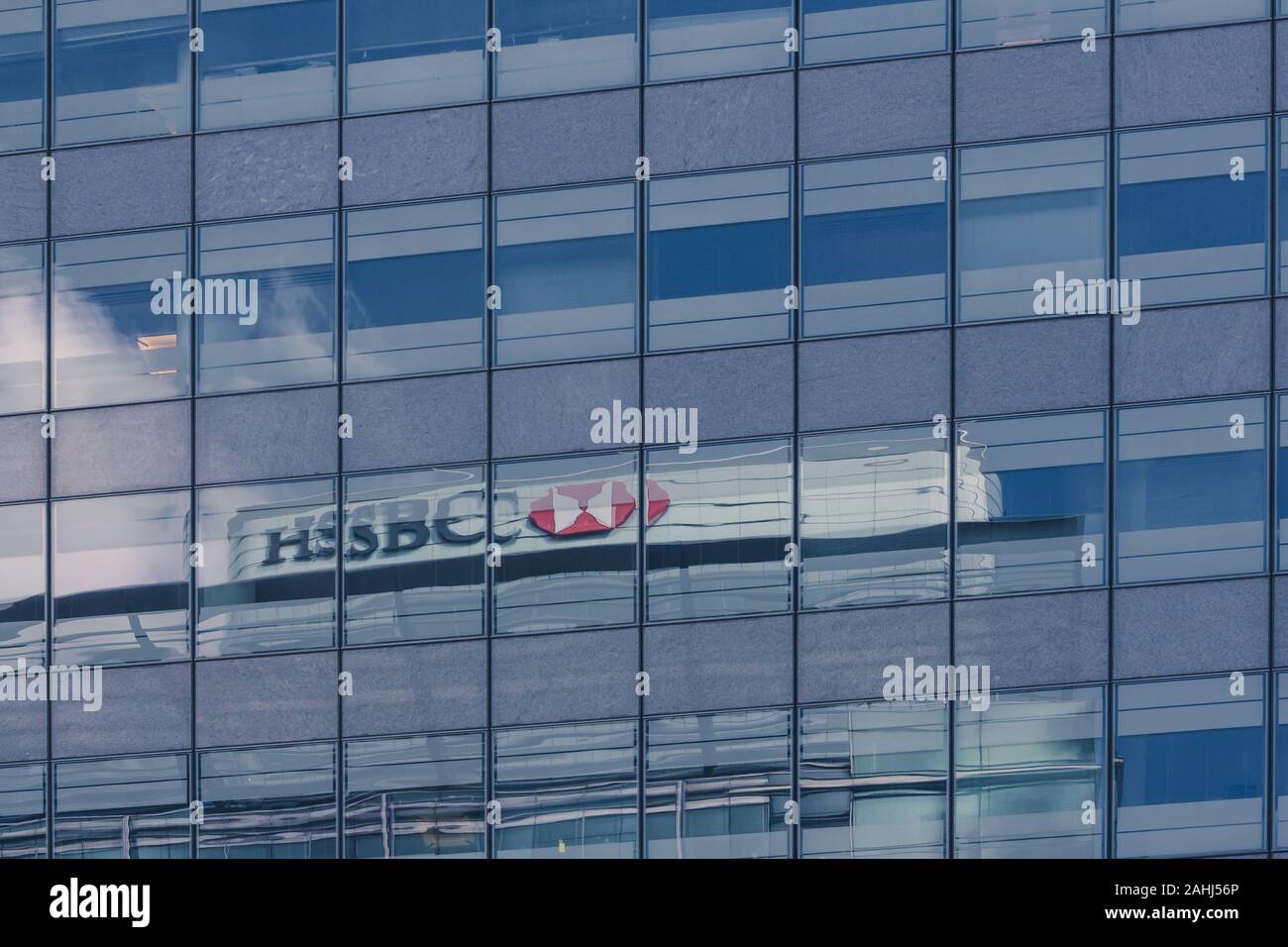 LONDON, ENGLAND - 27. AUGUST 2015: HSBC Global Headquarters in Canada Square, Canary Wharf, London in den Fenstern von einem modernen Bürogebäude wider Stockfoto