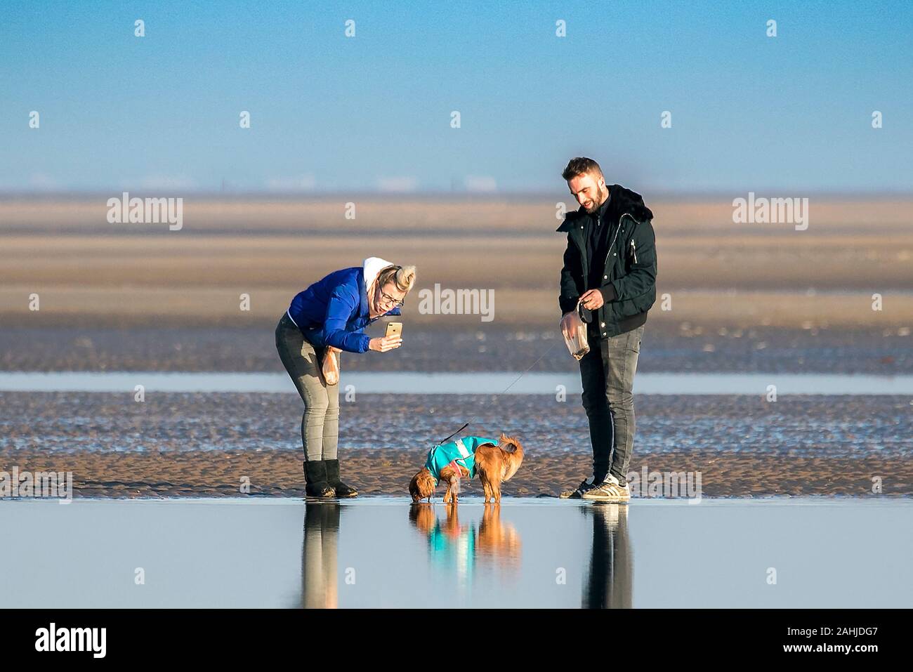 Southport, Merseyside, zum 30. Dezember 2019. Menschen für etwas Spaß in der Sonne mit ihren Hunden am Strand in Southport, Merseyside. Strahlender Sonnenschein und blauer Himmel Besucher der Badeort begrüßt wie der milde Winter Wetter während der Weihnachtsferien fort. Credit: cernan Elias/Alamy leben Nachrichten Stockfoto