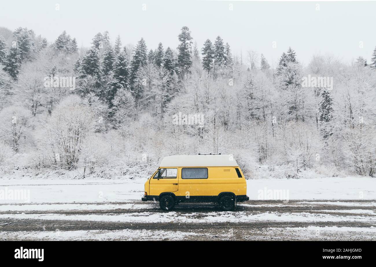 Karpaten, Ukraine - Dezember 2019: gelbe Wohnmobil mit winterlichen verschneiten Wald auf Hintergrund Stockfoto