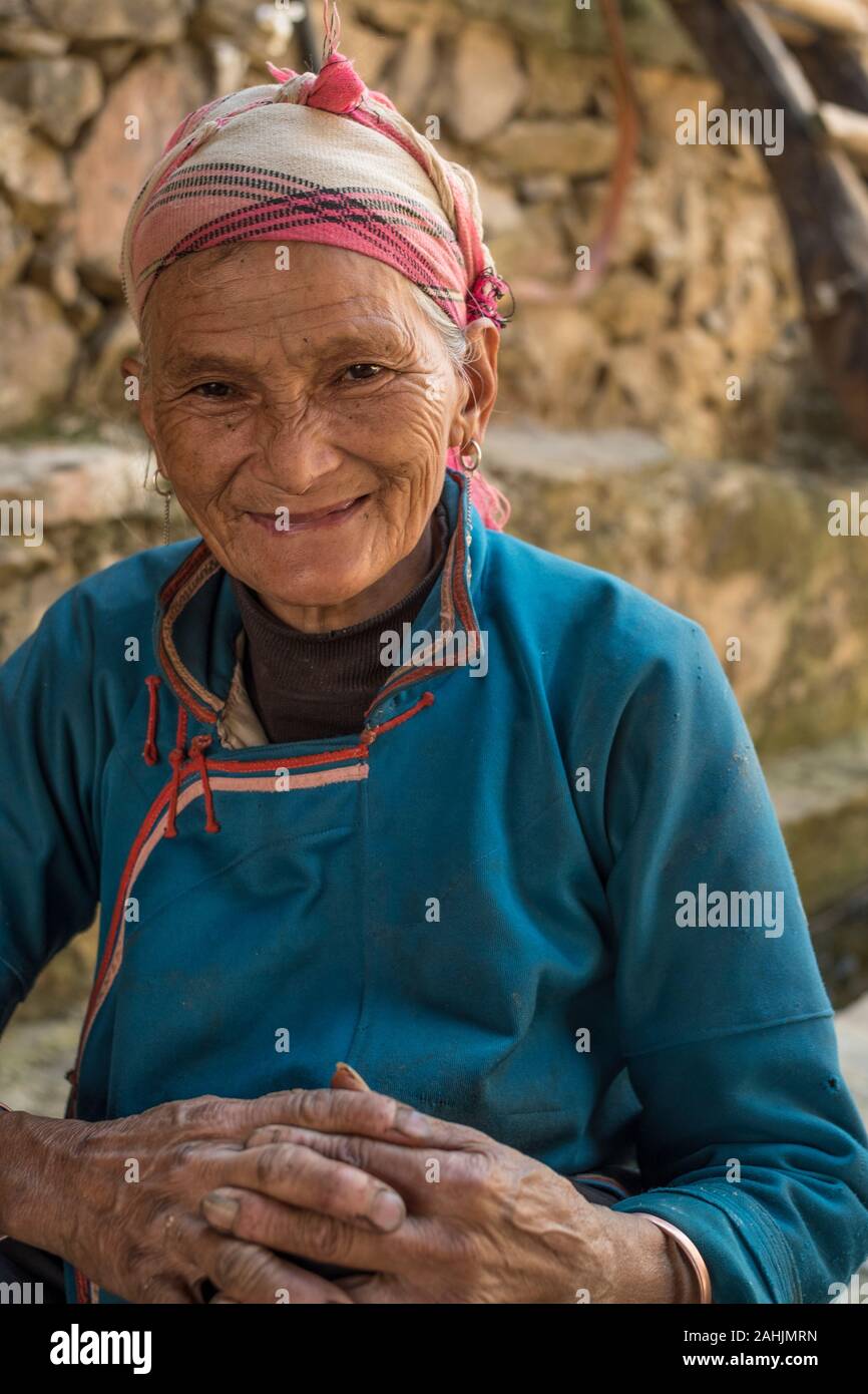Eine ältere Frau von Yi ethnische gruppe Rest in Cangtai Dorf mit traditionellen irdenen Wohnungen - tuzhangfang, Honghe, Yunnan, China. Stockfoto