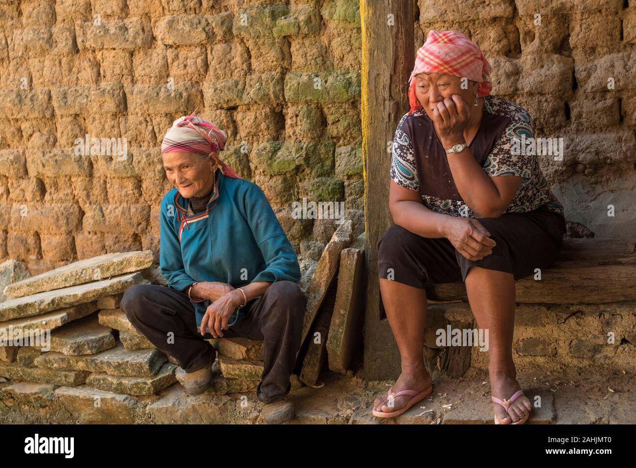 Ältere Frauen von Yi ethnische gruppe Rest in Cangtai Dorf mit traditionellen irdenen Wohnungen - tuzhangfang, Honghe, Yunnan, China. Stockfoto