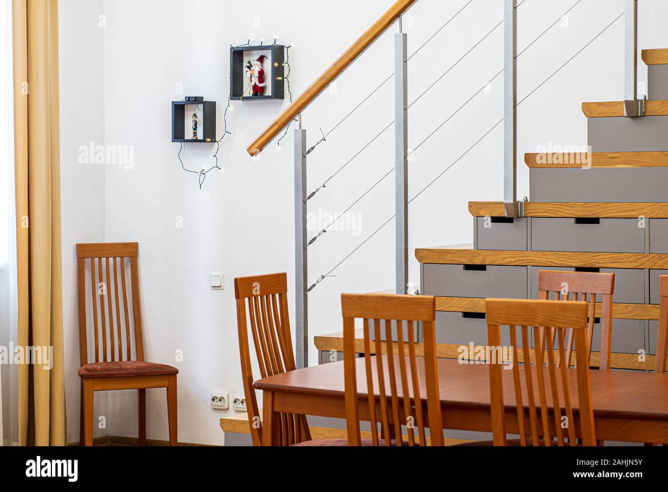 Holztisch und Stühlen. Treppe in den zweiten Stock. Weihnachten Dekorationen an der Wand. Stockfoto