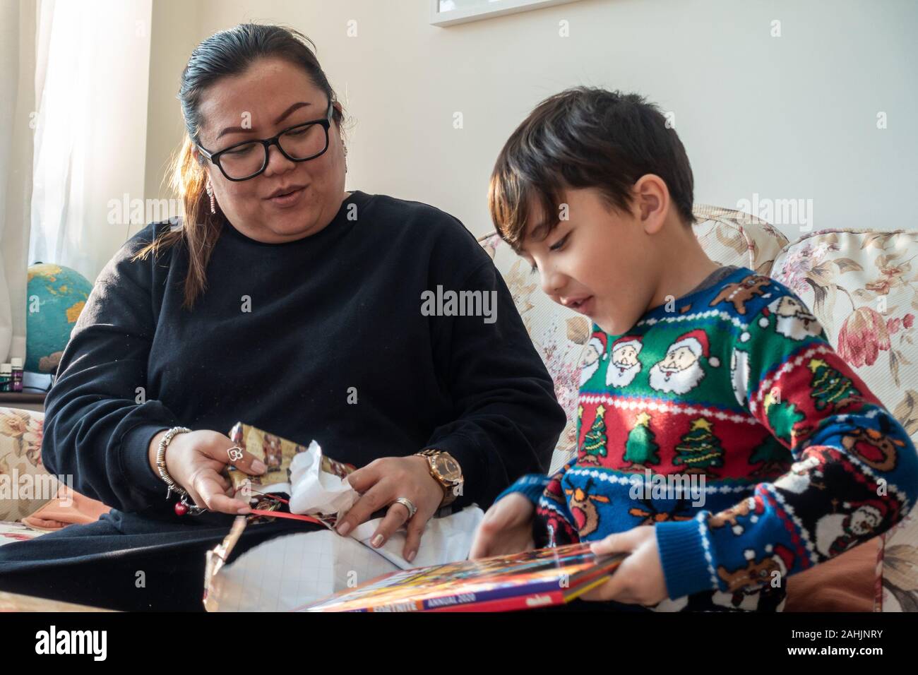 Eine Mutter und jungen Sohn aufgeregt ein Weihnachtsgeschenk gemeinsam öffnen Stockfoto