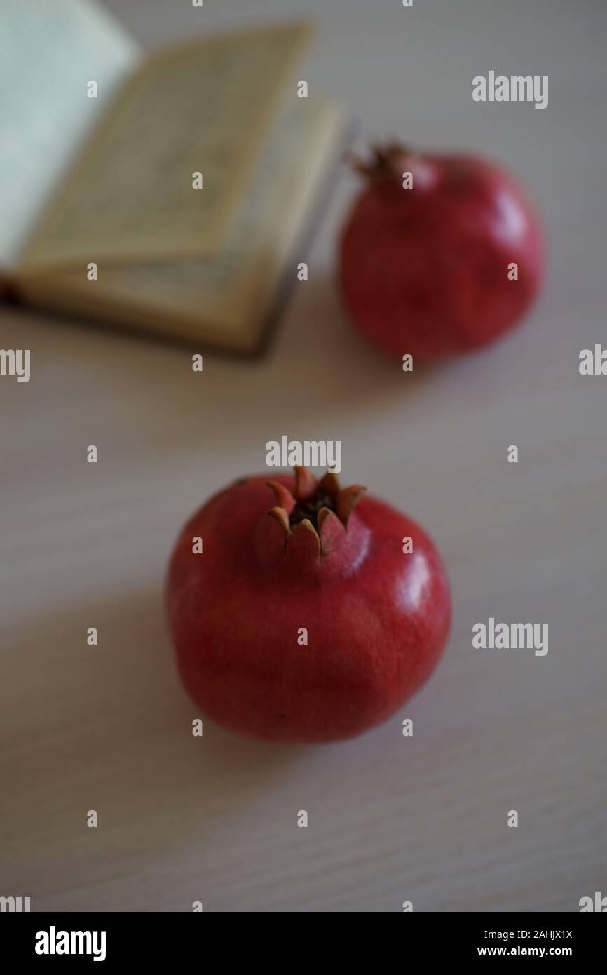 Zwei ganze reifer Granatapfel und eine offene Rezeptbuch auf einem Holztisch. Stockfoto