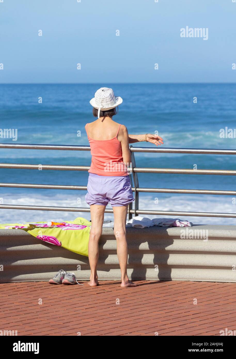 Ansicht der Rückseite des älteren Frau stretching Ovelooking das Meer. Stockfoto
