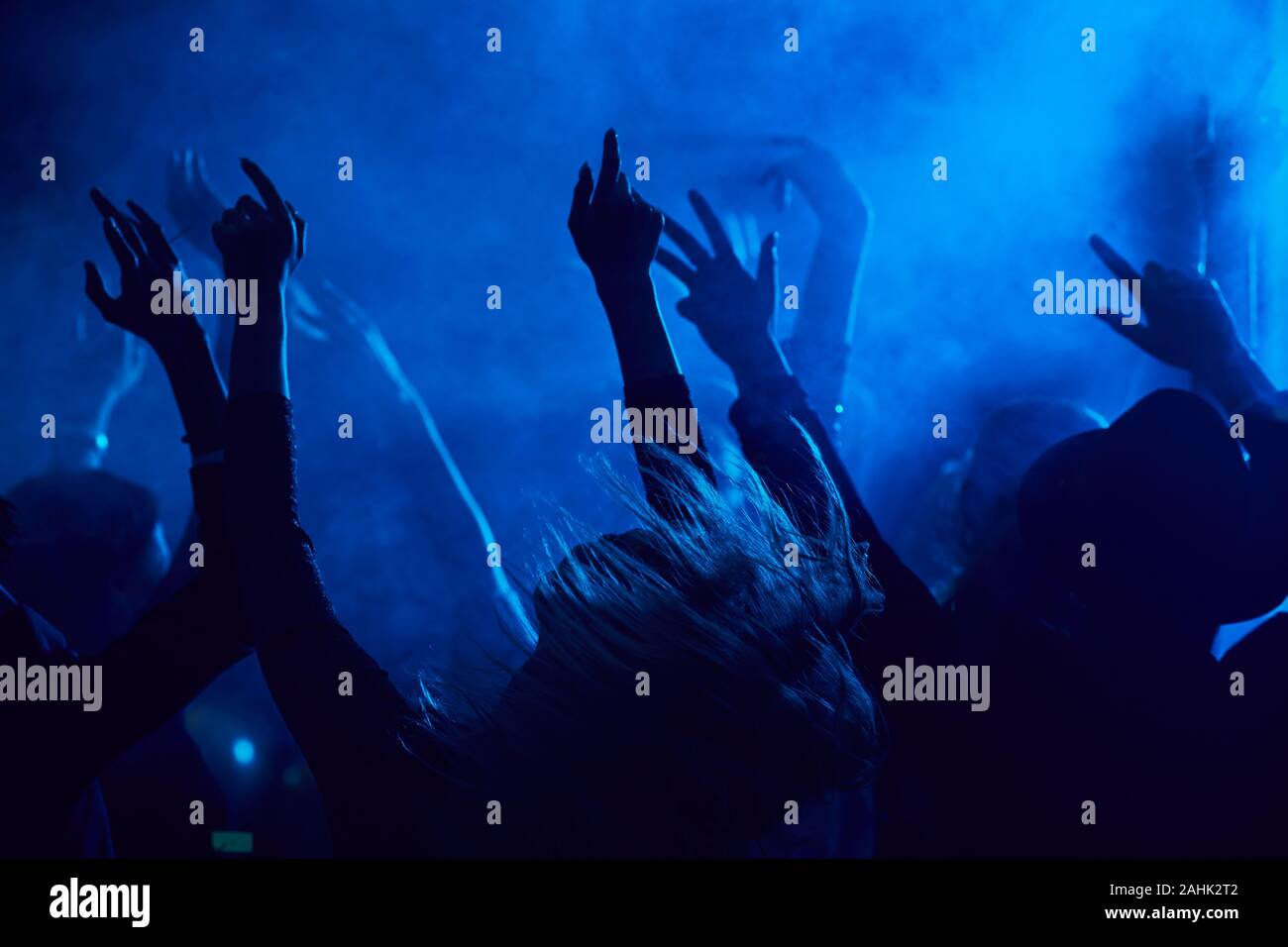 Silhouetten von Jugendlichen springen und heben die Hände beim Genießen der Musik Konzert in verrauchten Nachtclub durch blaues Licht leuchtet, kopieren Raum Stockfoto