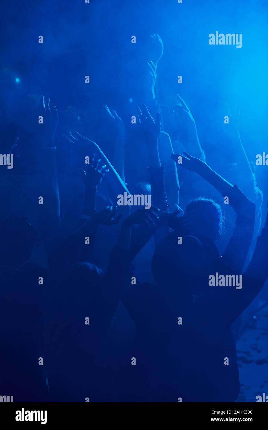 Silhouetten der großen Gruppe von Menschen tanzen und heben die Hände beim Genießen Partei in verrauchten Nachtclub beleuchtet durch blaues Licht, kopieren Raum Stockfoto