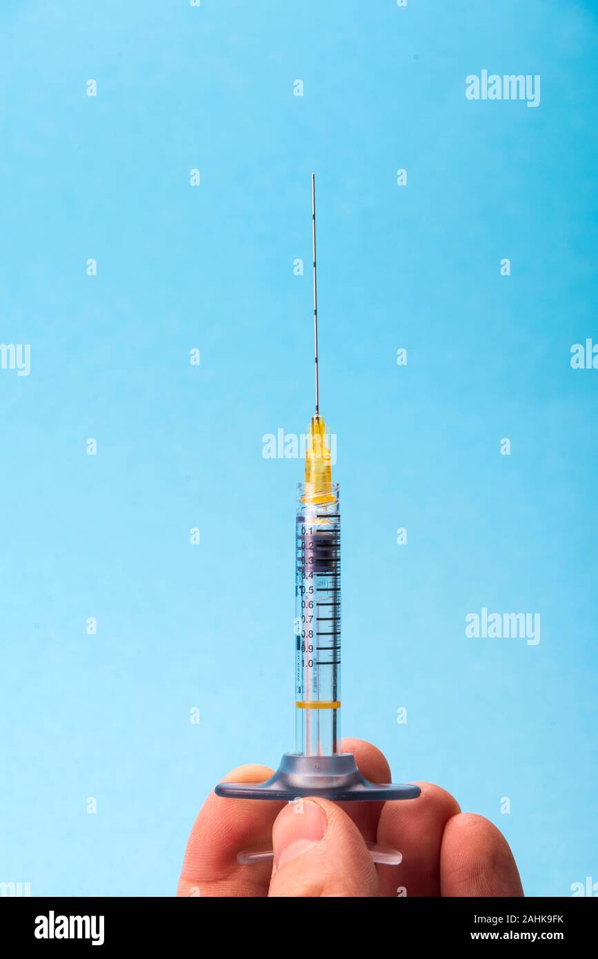 Medizinische Kunststoff Spritze mit einer Schönheit Injektionsnadel auf einem blauen Hintergrund in die Hand des Arztes Stockfoto