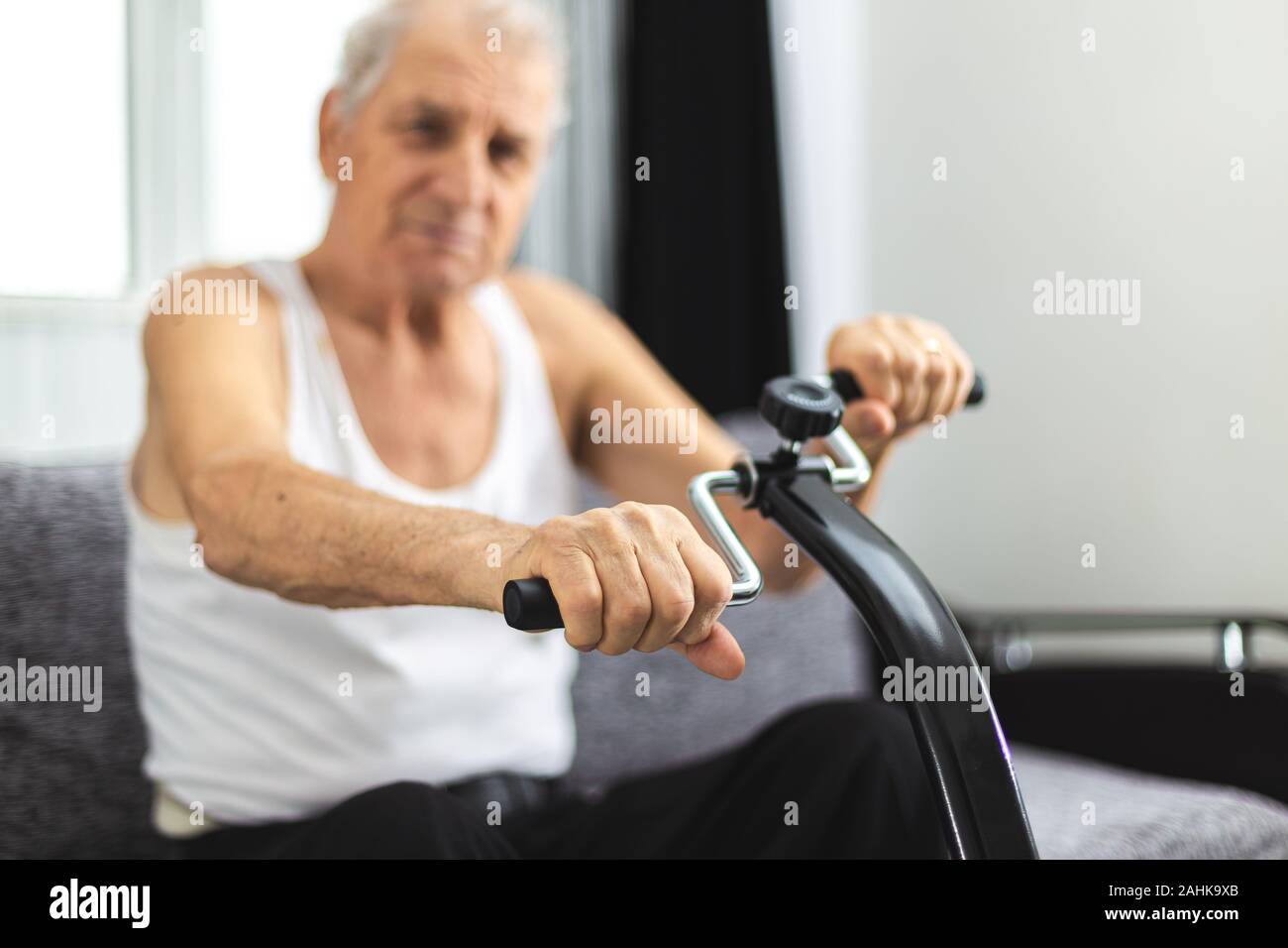 Älterer mann Training zu Hause. Älterer Mann übung zu Hause auf einem Fahrrad Gelenke in den Händen und in den Füßen zu erhalten Stockfoto