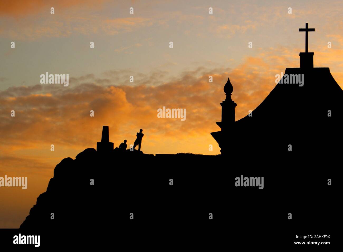 Kapelle mit Personensilhouette bei Sonnenuntergang. Contre-jour. Leça da Palmeira, Porto, Portugal. Stockfoto
