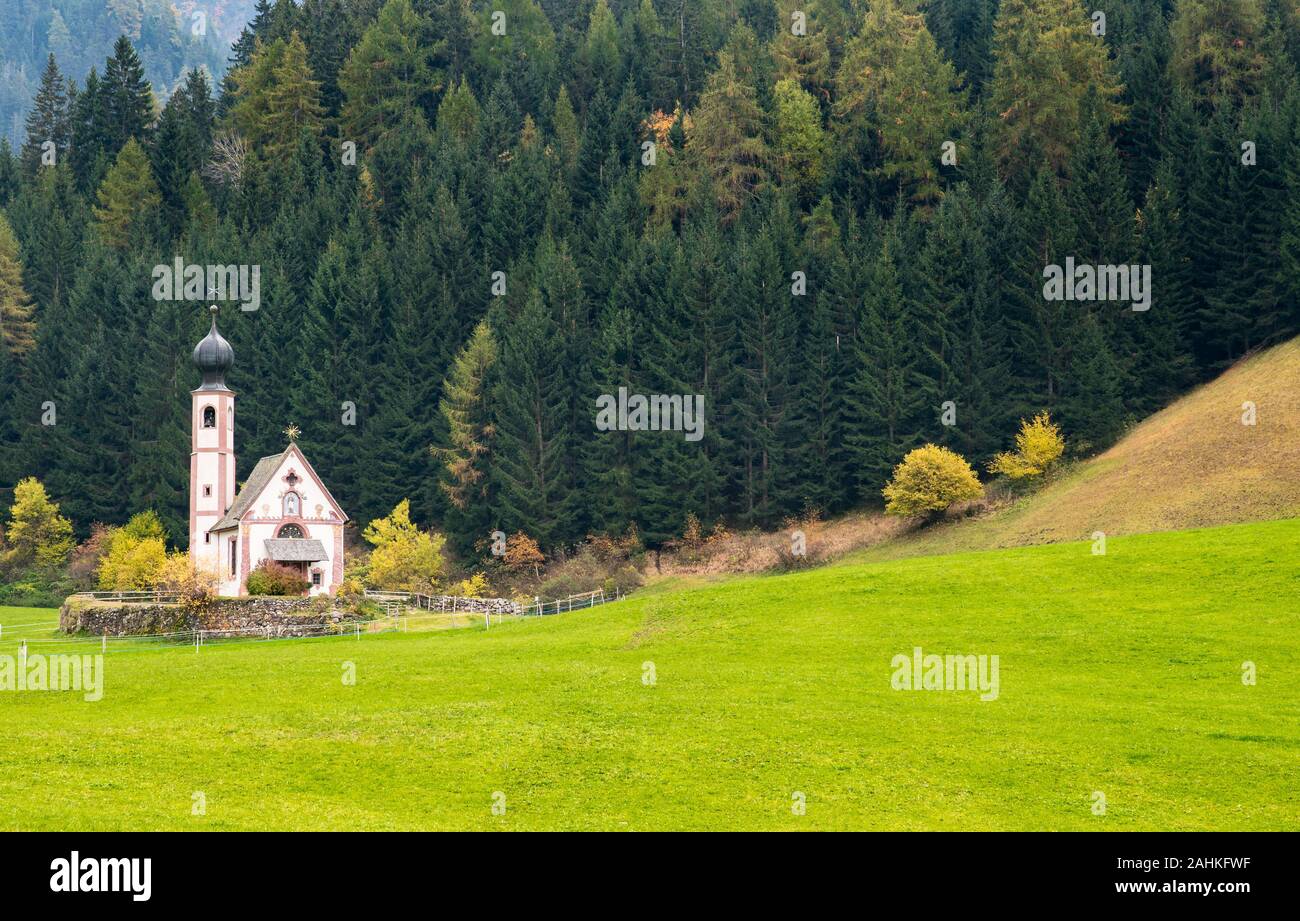 Die kleine und schöne Kirche des Heiligen Johannes, Ranui, chiesetta di San Giovanni in Ranui Runen Südtirol Italien, umgeben von grünen Wiesen, Wald ein Stockfoto