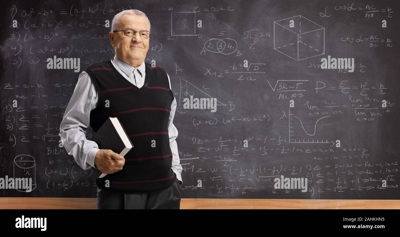 Ältere Professor mit einem Buch stand vor einer Tafel mit mathematischen Formeln Stockfoto