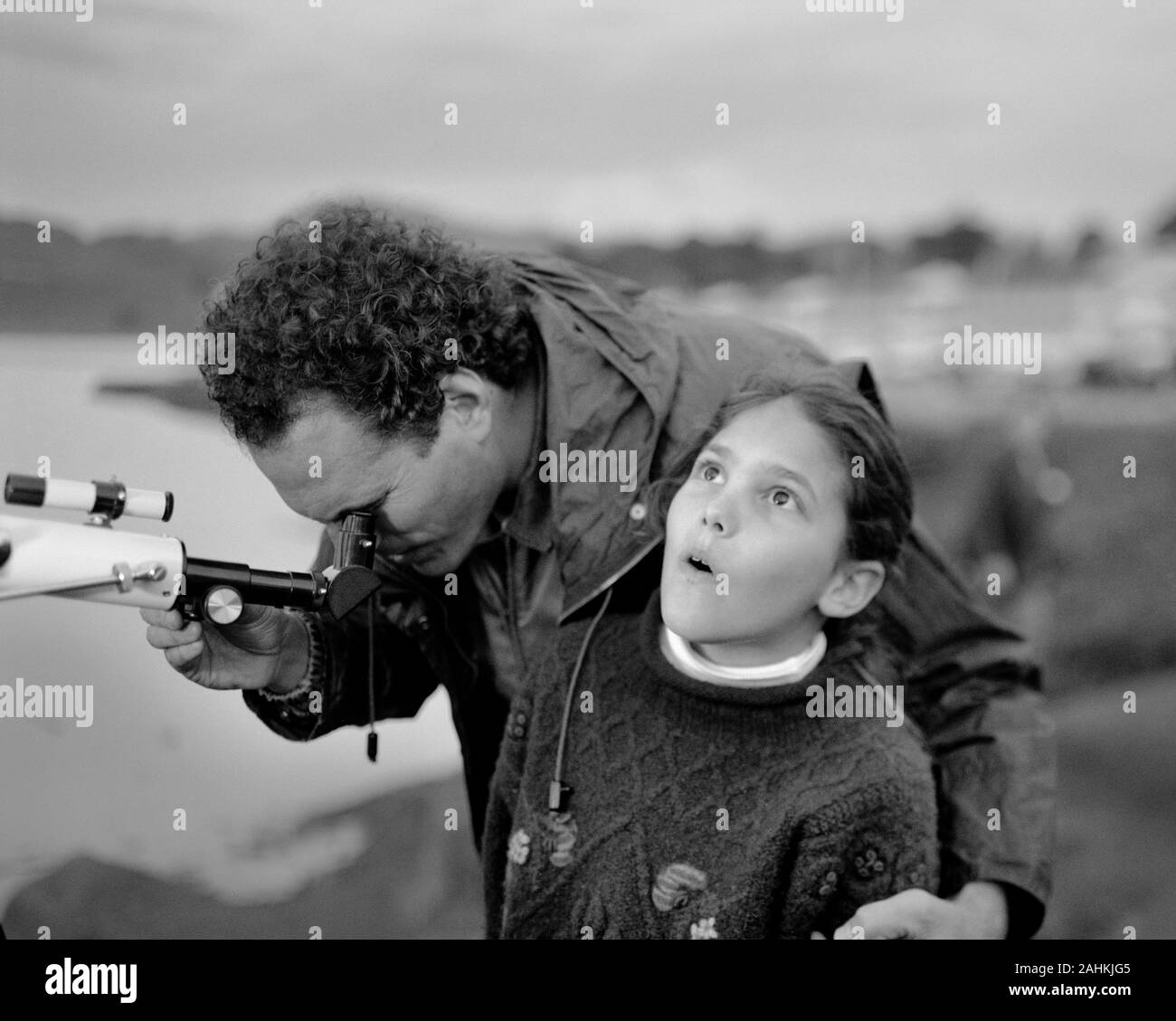 Mann, durch Teleskop als seine Tochter bis in den Himmel im Awe aussieht. Stockfoto