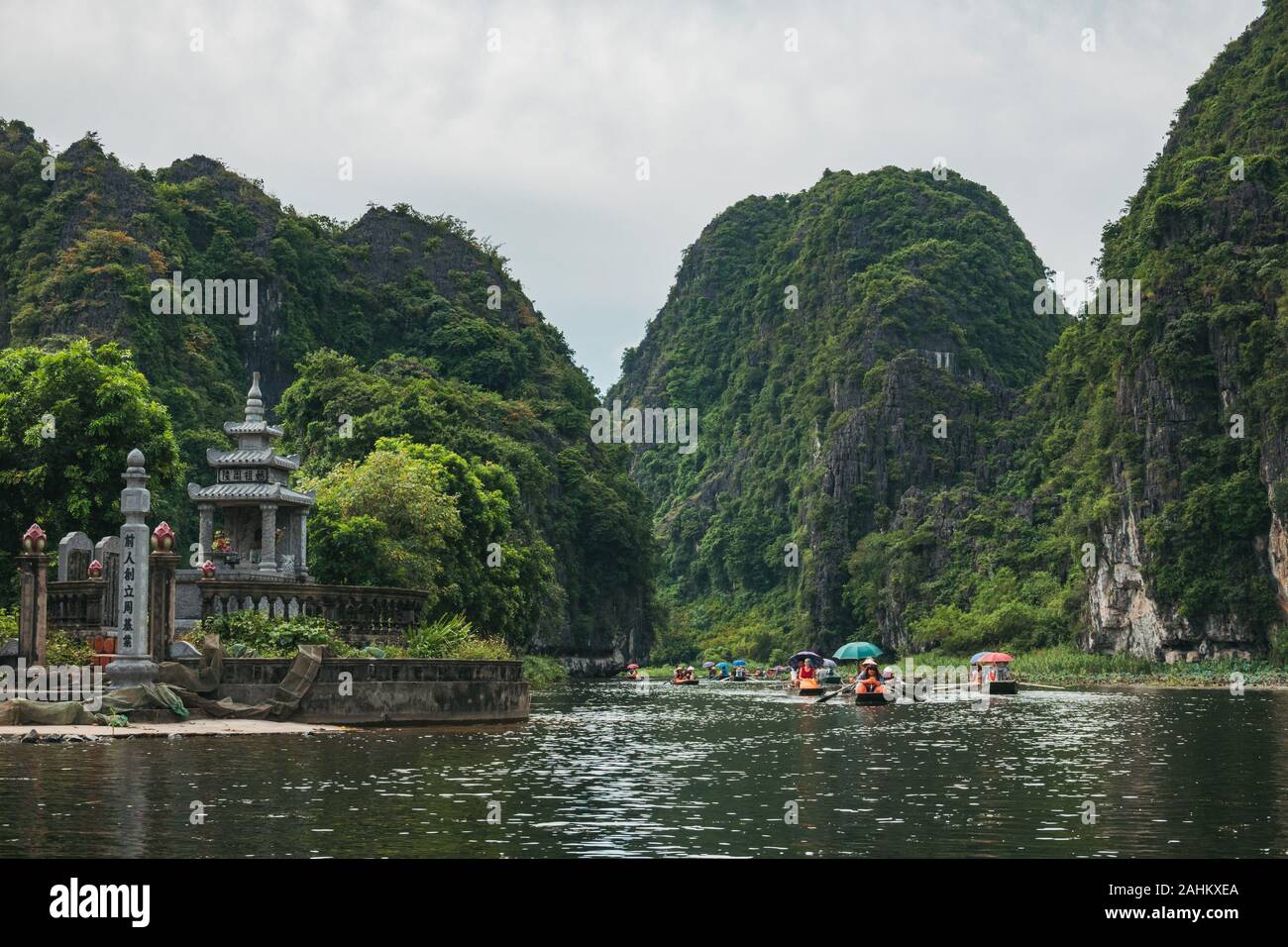 Touristen in Boote Zeile nach oben Die Ngo Dong Fluss durch Kalkstein Berge und Höhlen in der Tam Coc, Provinz Ninh Binh, Vietnam Stockfoto