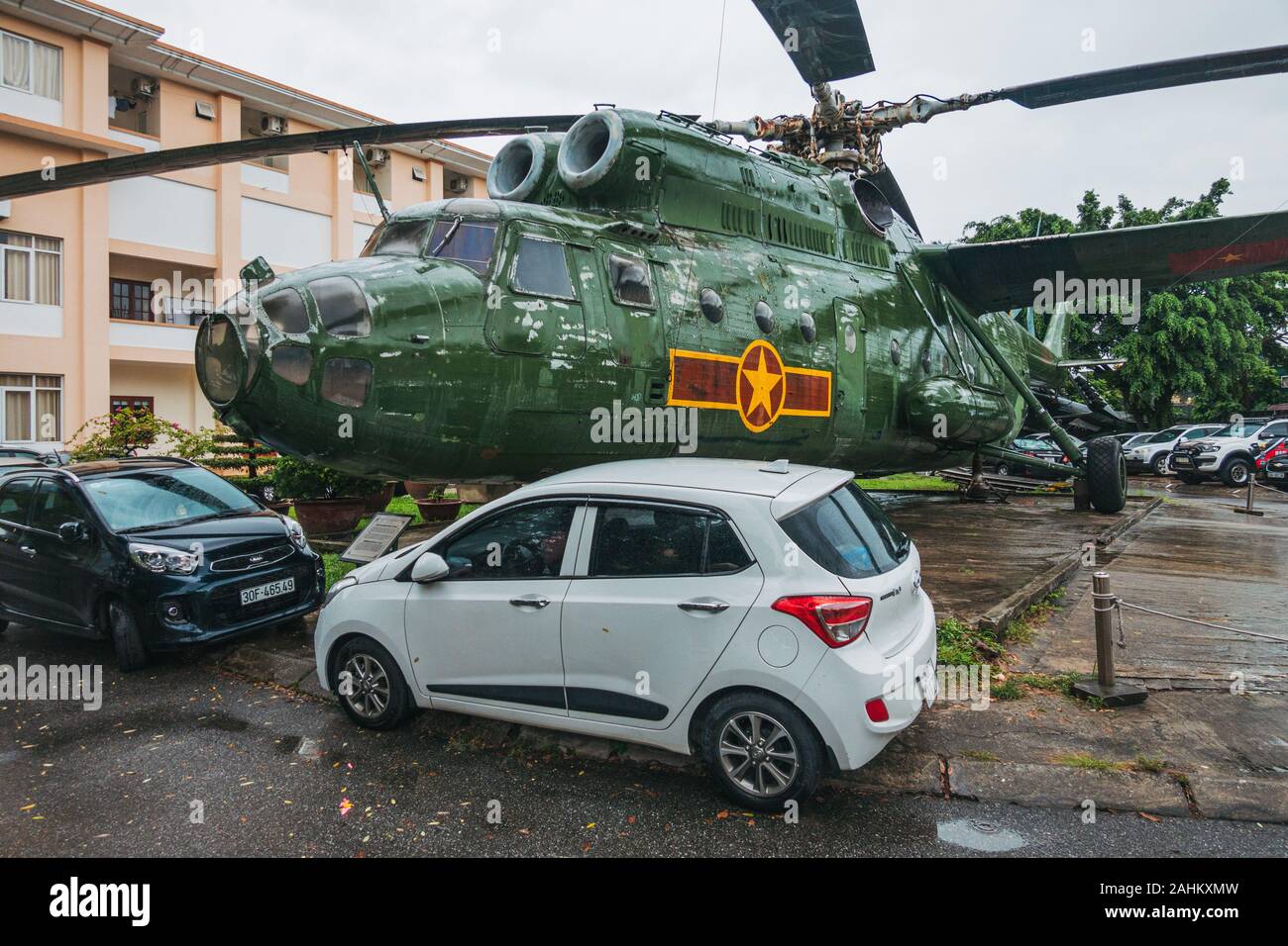 Eine riesige Mil Mi 6 Haken - ein militärischer Transporthubschrauber Zwerge Autos auf dem hinteren Parkplatz des Menschen in Vietnam Air Force Museum, Hanoi, Vietnam Stockfoto
