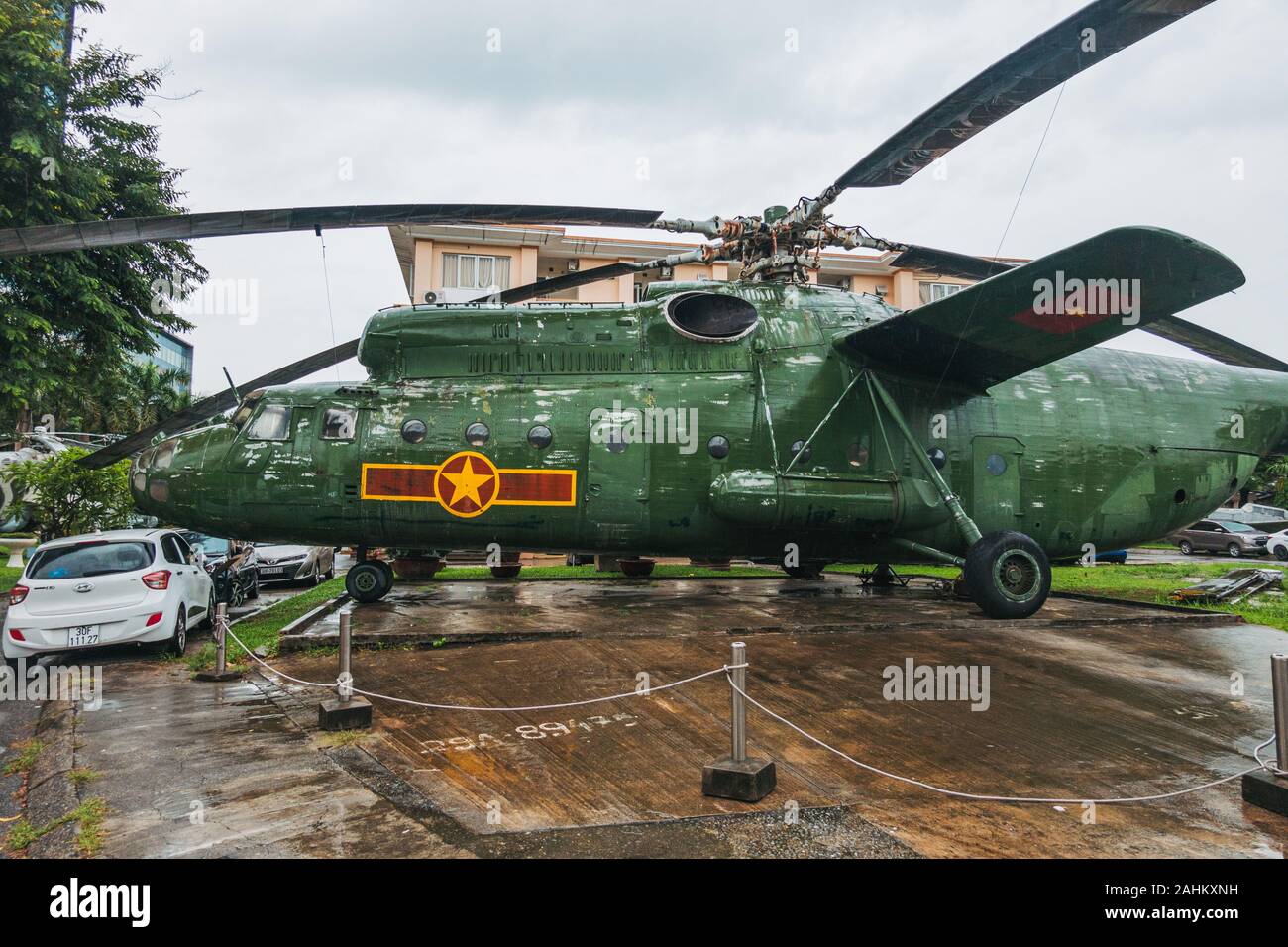 Eine riesige Mil Mi 6 Haken - ein militärischer Transporthubschrauber Zwerge Autos auf dem hinteren Parkplatz des Menschen in Vietnam Air Force Museum, Hanoi, Vietnam Stockfoto