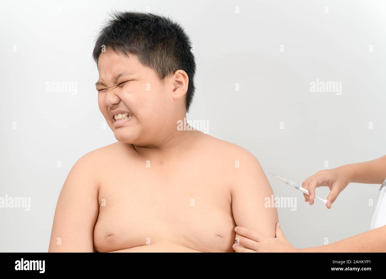 Fat Boy Angst vor der Spritze auf den Kopf weg drehen quetschen Augen in Angst. Medical Assistant eine intramuskuläre Injektion eines Impfstoffs zu seinen Arm. V Stockfoto