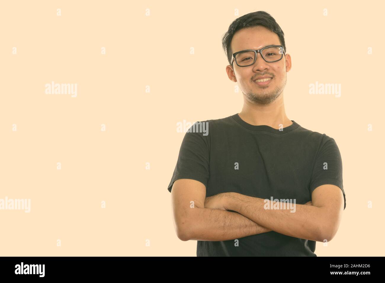 Studio shot junger asiatischer Mann glücklich lächelnd beim Tragen von Brillen mit gekreuzten Armen Stockfoto