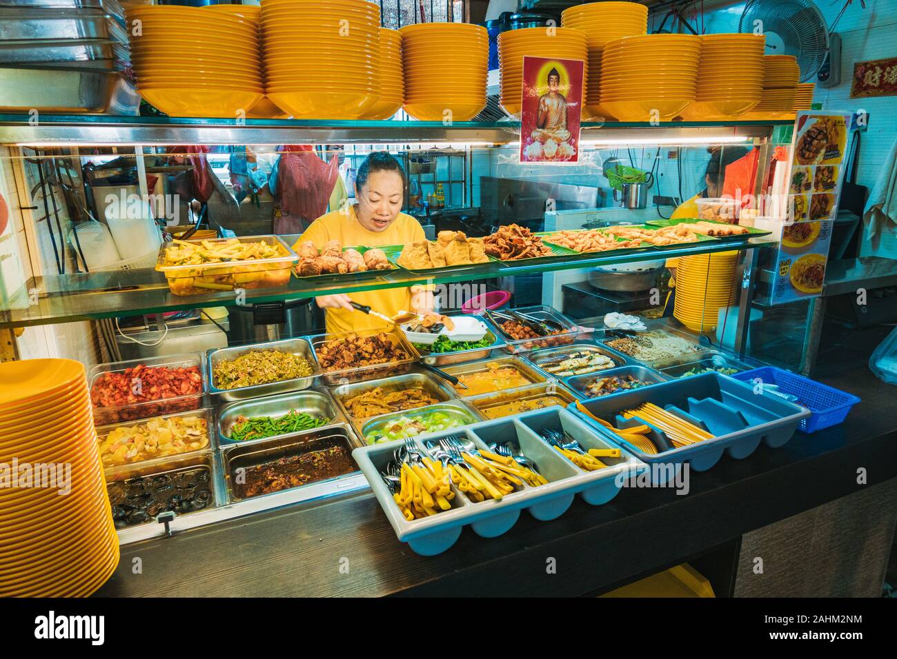 Eine Frau, die lufthutzen Essen auf einen Teller in einem Buddhistischen vegetarischen Essen in der Waterloo Food Centre, Singapur. Stockfoto