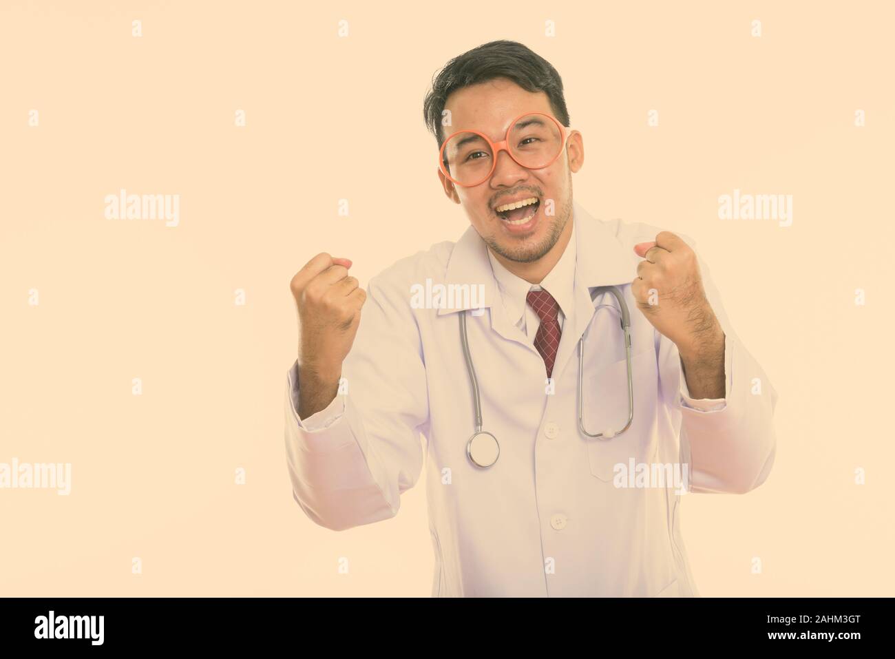Studio shot der Jungen glücklich asiatischer Mann Arzt lächelnd, während sie aufgeregt Stockfoto