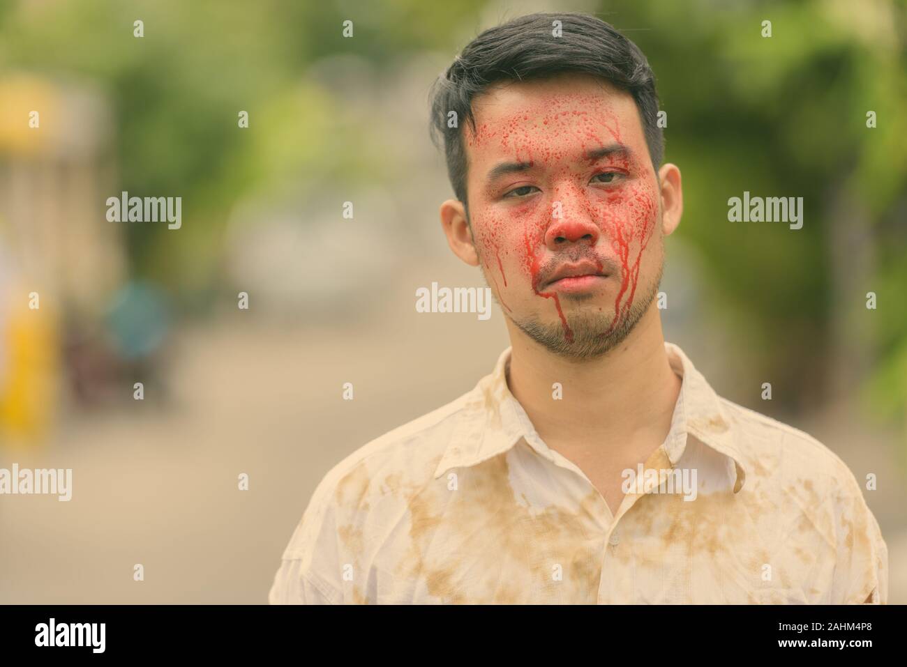 Junge verrückt asiatischer Mann mit Blut im Gesicht im Freien Stockfoto